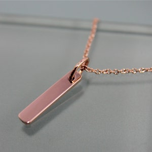 May include: A rose gold necklace with a simple, rectangular pendant. The pendant is smooth and polished, and the chain is delicate and dainty.