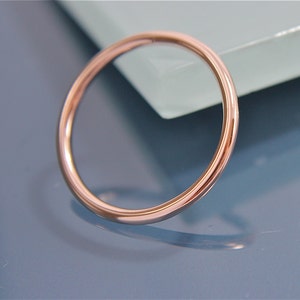 May include: A simple, polished, rose gold band ring.
