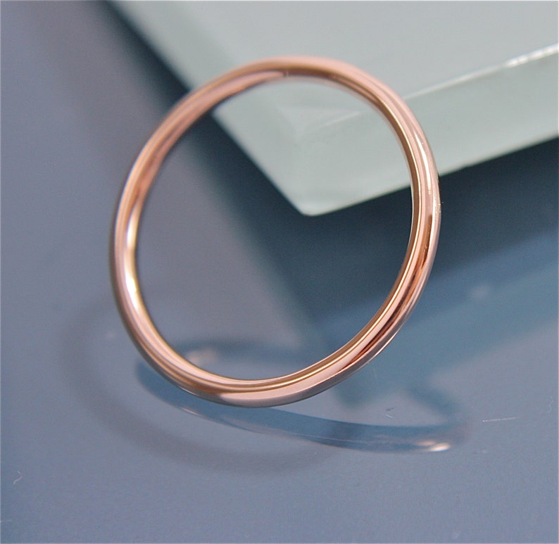 May include: A simple, polished, rose gold band ring.