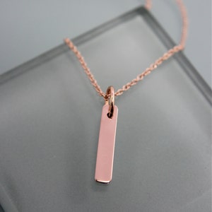 Puede incluir: Un delicado collar de oro rosa con un colgante rectangular simple.