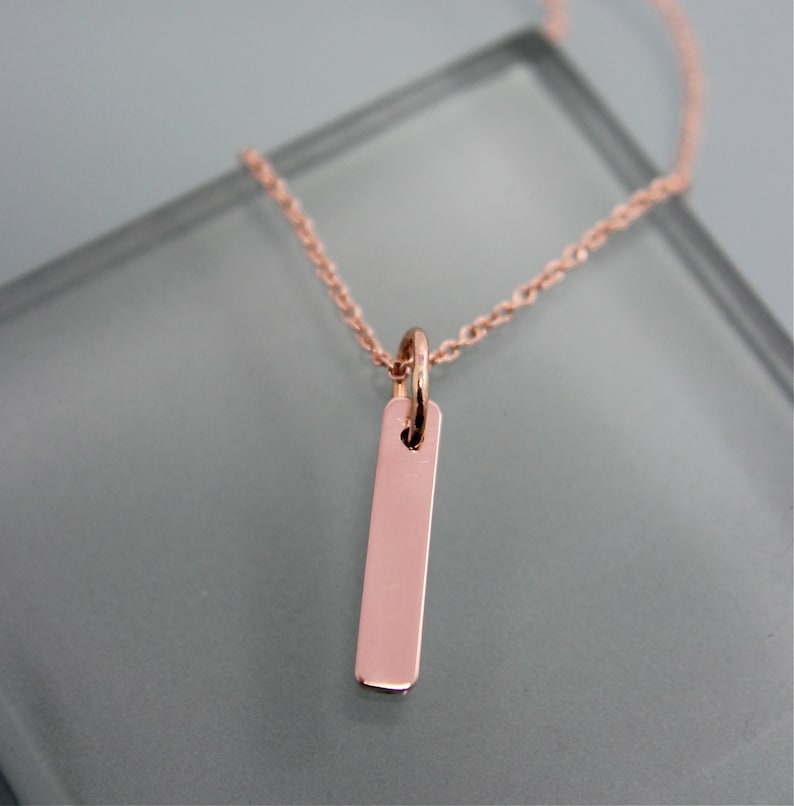 Puede incluir: Un delicado collar de oro rosa con un colgante rectangular simple.