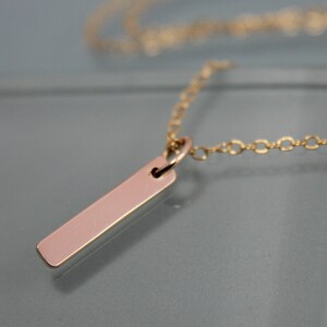 May include: A gold chain necklace with a thin, rectangular pendant.
