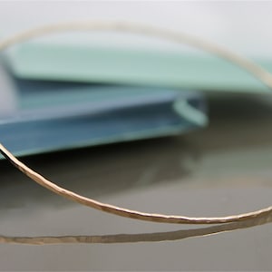 May include: A thin gold bangle bracelet with a hammered finish.