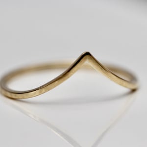 May include: A gold chevron ring with a hammered finish. The ring is simple and delicate, making it a great choice for everyday wear.