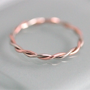 Peut inclure: Une fine bague tressée en deux métaux différents. La moitié de la bague est en argent et l'autre moitié en or rose.
