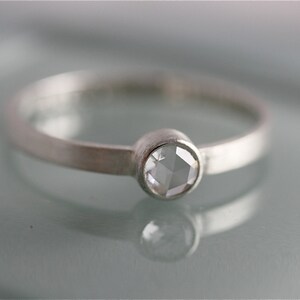 May include: A silver ring with a clear, faceted gemstone set in a bezel setting.