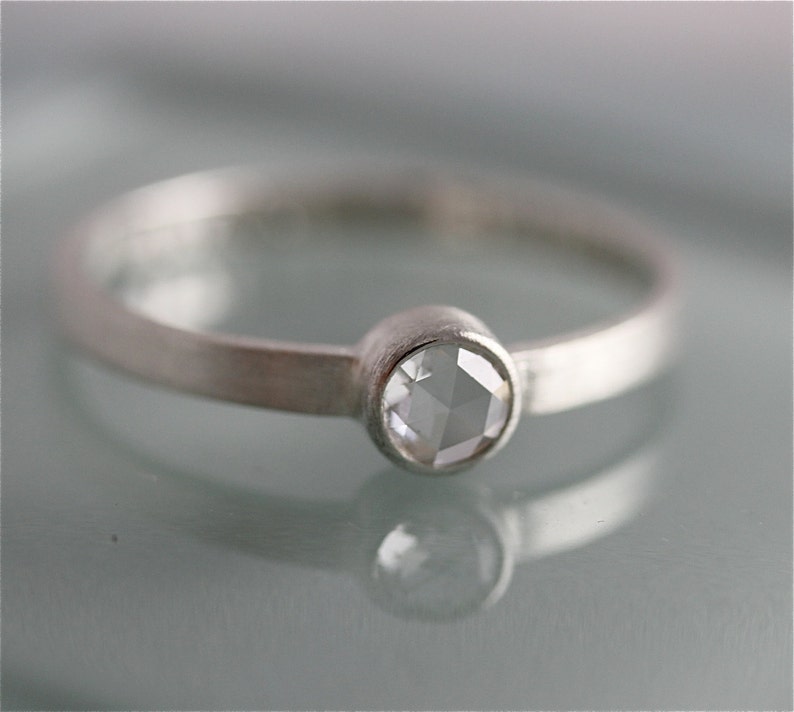 May include: A silver ring with a clear, faceted gemstone set in a bezel setting.