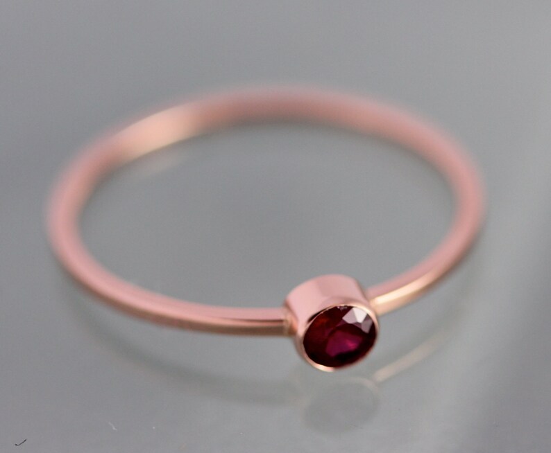 Op de afbeelding: Een eenvoudige ring van ros&eacute;goud met een enkele ronde rode robijn.