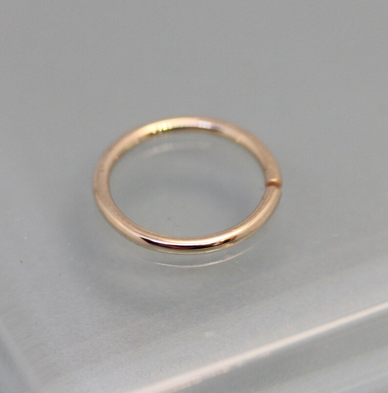 May include: A simple, smooth, gold-toned hoop earring. The hoop is seamless and has a polished finish.