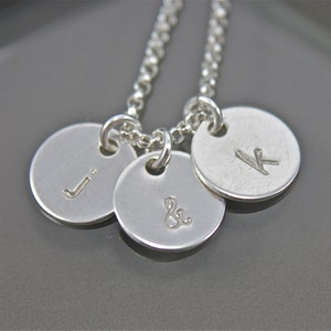 May include: Silver necklace with three round charms, each engraved with a letter: J, & and K.