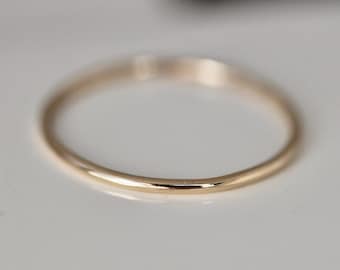 May include: A simple gold band ring with a smooth, rounded surface.