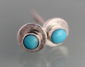 May include: A pair of silver earrings with turquoise stones. The earrings are round and have a simple design.