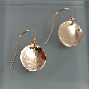 May include: A pair of gold-toned hammered disc earrings with a hook closure.