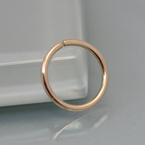May include: A gold-colored seamless hoop earring. The hoop is made of metal and has a smooth, polished finish.
