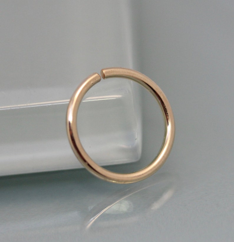 May include: A gold-colored seamless hoop earring. The hoop is made of metal and has a smooth, polished finish.