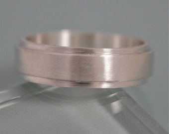 May include: A silver wedding band with a brushed finish and a subtle groove around the edge.