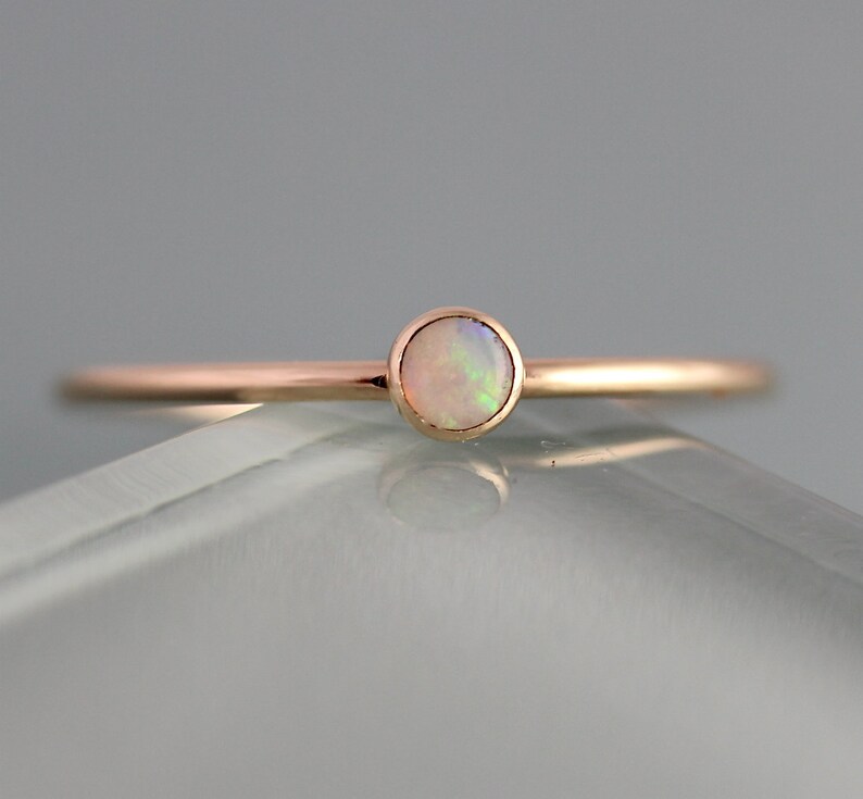 May include: A delicate rose gold ring with a single round opal gemstone.