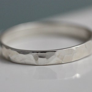 May include: A silver hammered band ring. The ring is a simple design with a hammered texture.