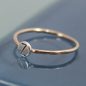 May include: A silver ring with a round, silver charm featuring the letter "Z" engraved on it.