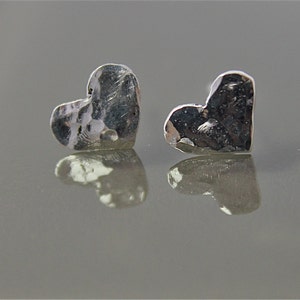 May include: A pair of silver heart-shaped earrings with a hammered texture.