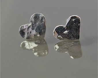 May include: A pair of silver heart-shaped earrings with a hammered texture.