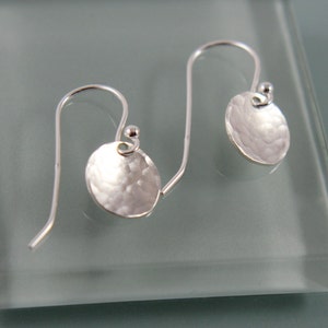 Peut inclure: Une paire de boucles d'oreilles en argent avec un disque martelé et une fermeture simple en fil.