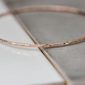 May include: A delicate rose gold bangle bracelet with a hammered finish.