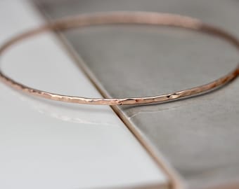 May include: A delicate rose gold bangle bracelet with a hammered finish.