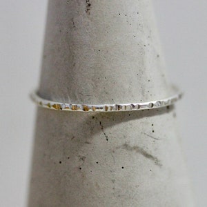 May include: A thin silver ring with a textured band.