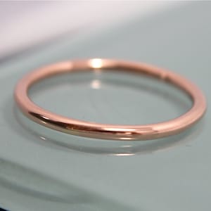 May include: A simple, thin rose gold band ring.