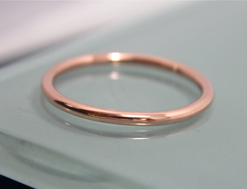 May include: A simple, thin rose gold band ring.