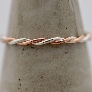 May include: A twisted band ring in silver and rose gold.