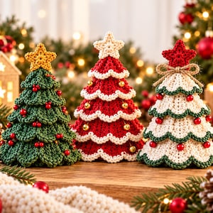 May include: Three crocheted Christmas tree ornaments. The left tree is green with red berries and a yellow star. The center tree is red with white trim and a white star. The right tree is white with green trim, red berries, and a red star.