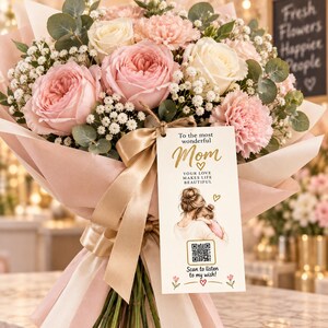 May include: A bouquet of light pink and white roses, carnations, and eucalyptus leaves wrapped in pink paper. A gold ribbon holds a rectangular tag with the text To the most wonderful Mom, Your love makes life beautiful, and a QR code.