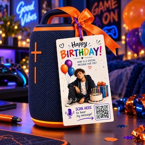 May include: A dark blue portable speaker with orange accents and a handle, featuring a rectangular gift tag tied with an orange ribbon. The tag displays the text Happy Birthday, an illustration of a person, a birthday cake, and a QR code.