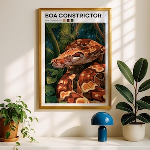 May include: A framed wall art print featuring a detailed illustration of a Boa Constrictor snake coiled among green foliage. The text BOA CONSTRICTOR and Boa Constrictor is printed at the top, accompanied by three small color squares in tan, brown, and green.