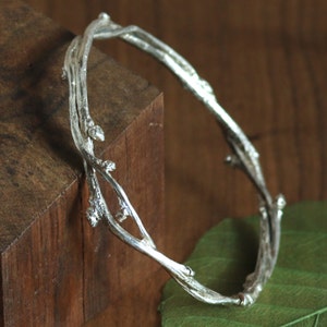 Sterling Silver Twig bangle bracelet Wild Bittersweet Vine.

Wild bittersweet vine is picked in the springtime and woven into a bangle and cast in sterling silver. It retains all of the budding characteristics of the vine.