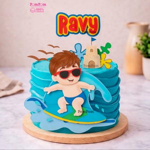 Puede incluir: Un set de decoración para pastel azul con un niño de dibujos animados con cabello castaño y gafas de sol rojas surfeando en una tabla azul y verde. Incluye un castillo de arena beige, pájaros marrones y un letrero rojo y amarillo con el nombre Ravy.