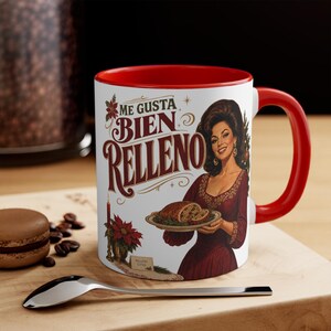 Peut inclure: Un mug en céramique blanche avec un intérieur et une anse rouge vif. L'extérieur présente une illustration de style vintage d'une personne en robe rouge foncé tenant un plateau avec un pain, accompagnée du texte ME GUSTA BIEN RELLENO.