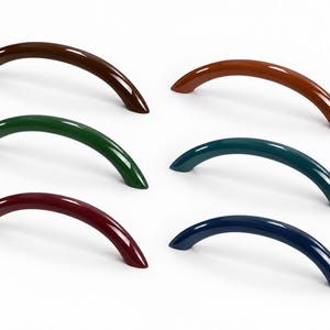 May include: Six arched cabinet handles with a smooth, glossy finish, arranged in two vertical columns. The colors include dark brown, forest green, deep red, terracotta orange, teal, and navy blue, each featuring a curved, solid design.