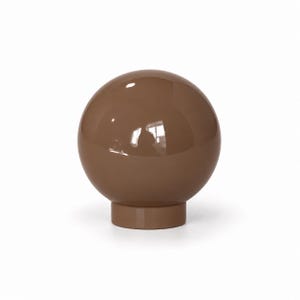 May include: A smooth, glossy, spherical object in a solid brown color. The sphere is mounted on a short, cylindrical base of the same matching brown tone, creating a uniform and polished appearance with reflective highlights on the surface.