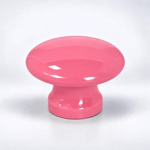 May include: A solid, glossy pink cabinet knob with a smooth, rounded top and a cylindrical base. The hardware features a reflective, polished finish that catches the light, creating a uniform, vibrant pink color across the entire surface.