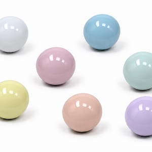 May include: A collection of seven smooth, spherical objects in various pastel colors including white, light blue, pale pink, mint green, soft yellow, peach, and lavender. Each sphere features a glossy, reflective finish with a bright highlight.