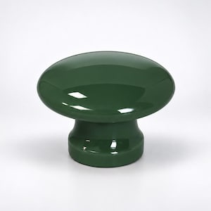 May include: A solid dark green cabinet knob with a smooth, glossy finish. The knob features a wide, rounded top surface that tapers down into a cylindrical base, creating a mushroom-like shape. The surface reflects light clearly.