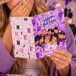 May include: A purple-themed birthday greeting card featuring a group photo of seven individuals, the text Happy Birthday, and a pattern of logos. The card is held open, displaying a collage of images and decorative elements in shades of purple and white.