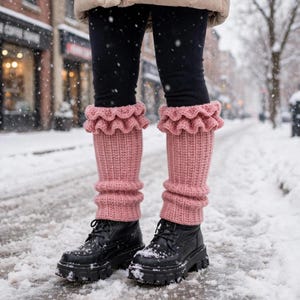 Puede incluir: Un par de calentadores de punto acanalado en color rosa empolvado con un borde superior con volantes. Los calentadores se llevan sobre mallas negras y se combinan con botas negras con cordones, sobre una calle nevada en invierno.