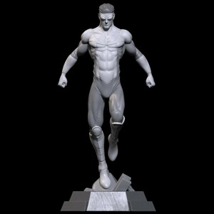 Könnte beinhalten: Eine monochrome graue Figur eines muskulösen Superhelden in einer dynamischen Flugpose. Die Figur zeigt ein definiertes Brustemblem, Stulpen und Stiefel und steht auf einem rechteckigen Sockel mit einem zentralen, texturierten Paneel.
