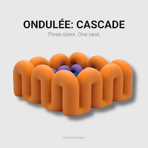 May include: An orange, wavy, square-shaped container with a hollow centre containing small purple and blue spheres. The text ONDULÉE: CASCADE, Three sizes. One nest. and PrinTerra Designs are visible above and below the object.