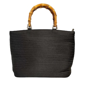Puede incluir: Un bolso de mano negro con una superficie texturizada de rayas horizontales y un asa redondeada de bambú en color natural. El bolso cuenta con herrajes de metal plateado que conectan el asa con el cuerpo principal del bolso estructurado.