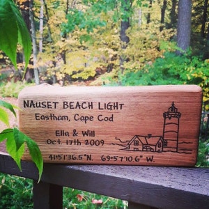 Puede incluir: Un letrero de madera con el texto "Nauset Beach Light Eastham, Cape Cod Ella & Will Oct. 17th 2009 41°51′36.5"N. 69°57′10.6" W." y una ilustración en blanco y negro de un faro y una casa.
